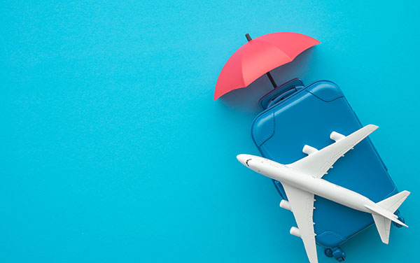 Travel insurance business concept. Red umbrella cover airplane and suitcases on blue background. Travel insurance covers loss suitcase, flight delays, cancellations, accident and medical expenses.